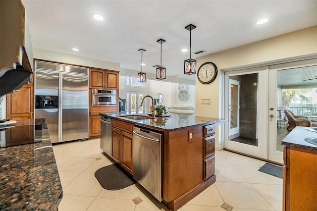 kitchen featuring appliances with stainless steel finishes, brown cabinetry, light tile patterned flooring, and a sink