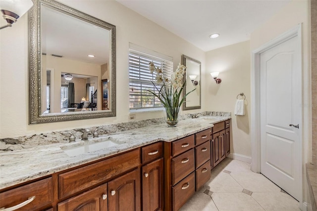 bathroom featuring baseboards, double vanity, a sink, and tile patterned floors