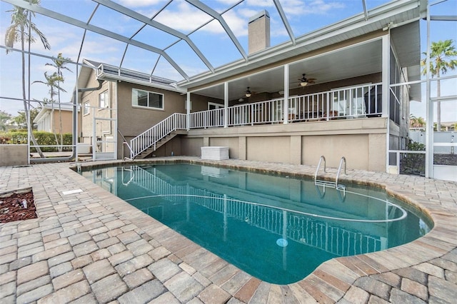 pool with glass enclosure, a patio, and ceiling fan