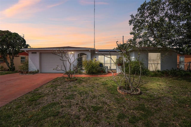 mid-century home featuring driveway, a front yard, and stucco siding