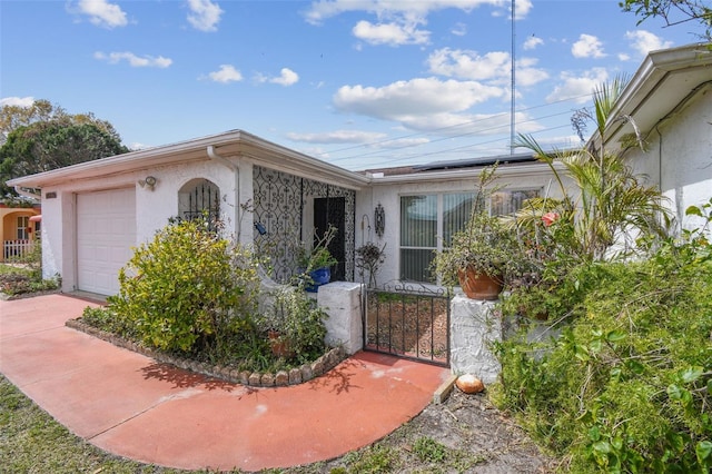 single story home featuring a garage, fence, concrete driveway, roof mounted solar panels, and stucco siding