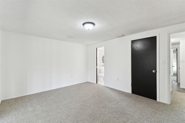 unfurnished bedroom featuring carpet floors, visible vents, connected bathroom, and a textured ceiling