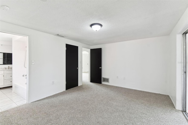 unfurnished bedroom featuring light carpet, a textured ceiling, a sink, and visible vents