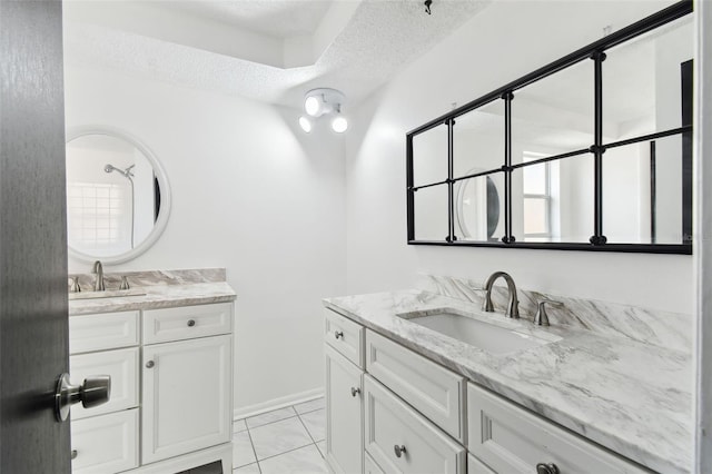 bathroom featuring a textured ceiling, two vanities, a sink, and baseboards