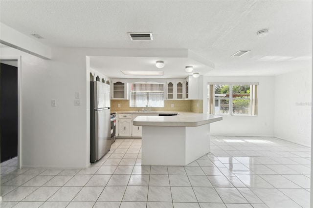 kitchen featuring visible vents, light countertops, light tile patterned floors, and freestanding refrigerator