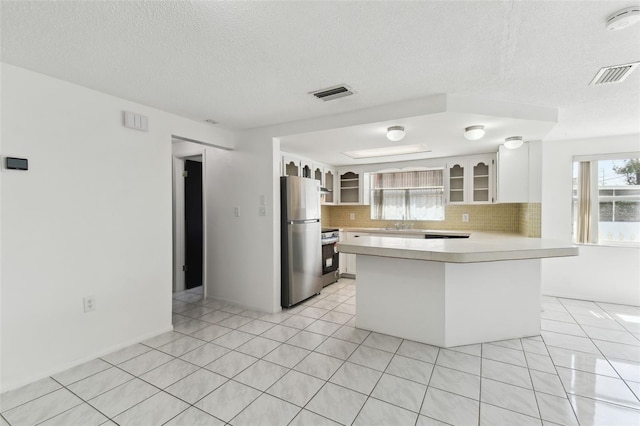 kitchen with a peninsula, appliances with stainless steel finishes, light countertops, and visible vents