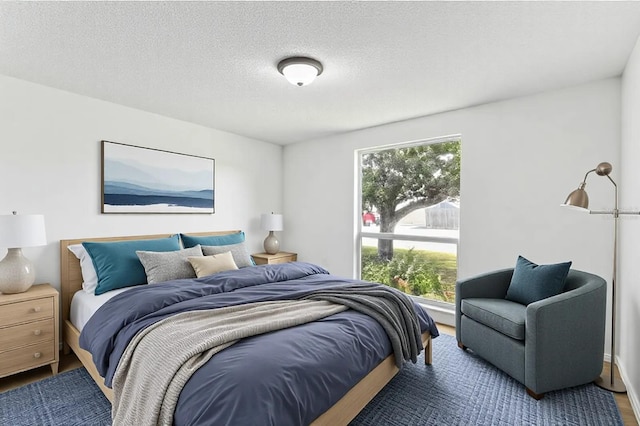 bedroom with a textured ceiling, multiple windows, and wood finished floors