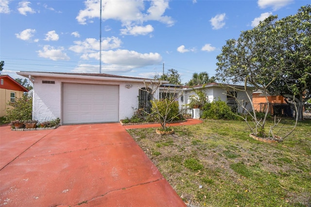 ranch-style home with a garage, driveway, a front yard, and stucco siding