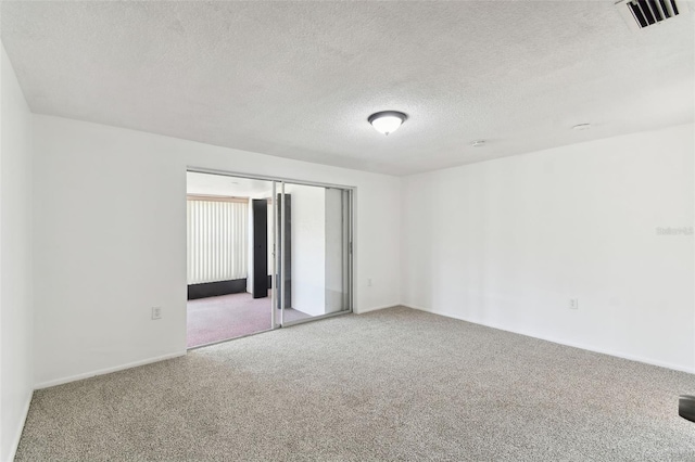 carpeted empty room with a textured ceiling and visible vents