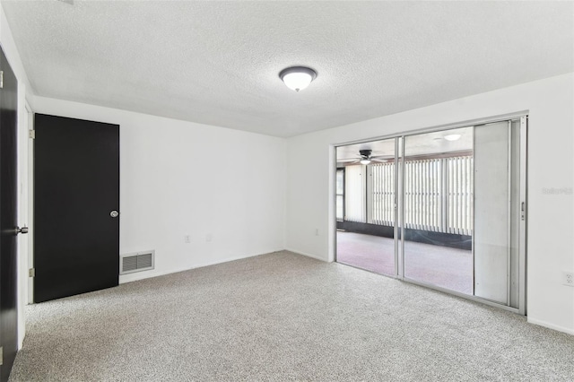 carpeted spare room with visible vents and a textured ceiling