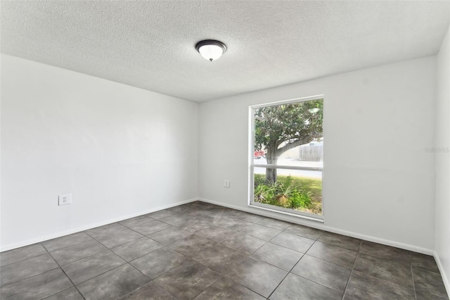 empty room featuring a textured ceiling and baseboards