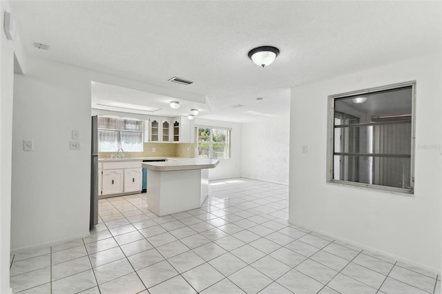 kitchen featuring light countertops, visible vents, decorative backsplash, glass insert cabinets, and white cabinetry