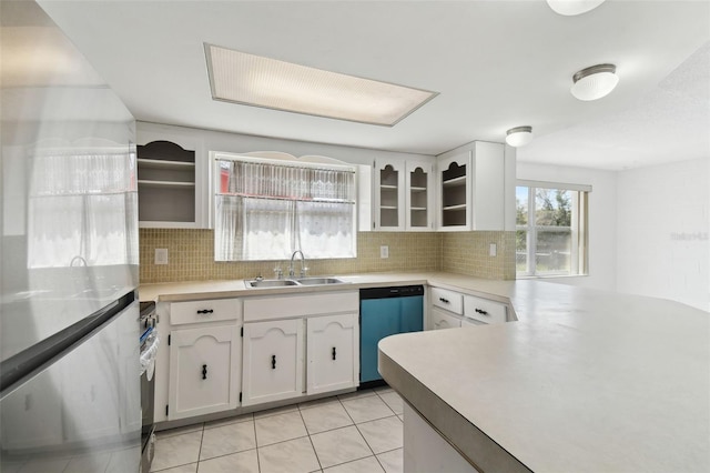 kitchen with decorative backsplash, dishwashing machine, glass insert cabinets, white cabinetry, and a sink