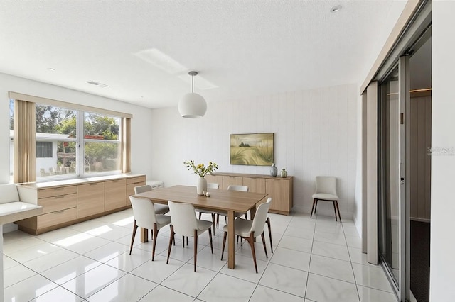 dining room with light tile patterned floors, visible vents, and a textured ceiling