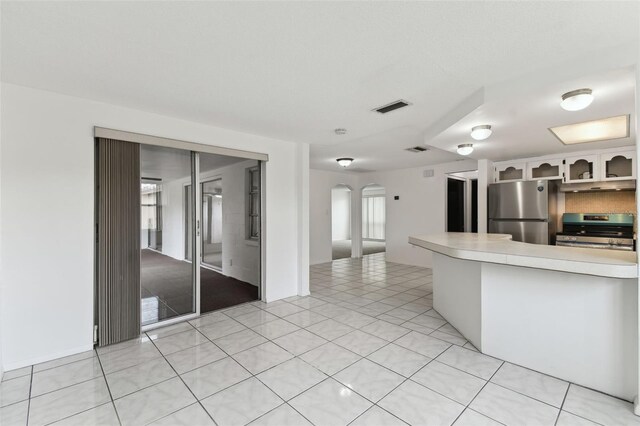 kitchen with visible vents, arched walkways, appliances with stainless steel finishes, light countertops, and light tile patterned flooring