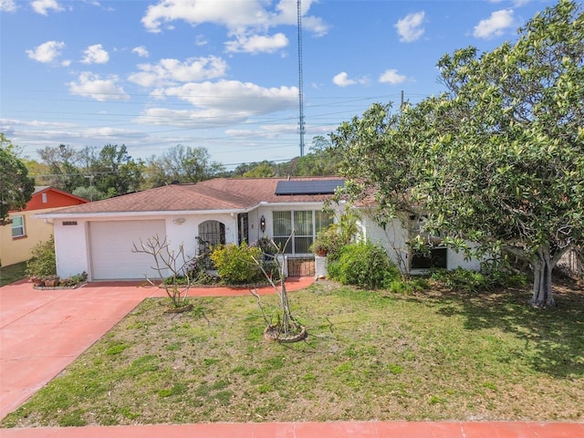 view of front of property featuring a garage, driveway, stucco siding, roof mounted solar panels, and a front yard