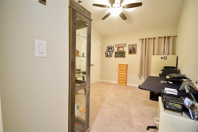 office space featuring a ceiling fan, light colored carpet, vaulted ceiling, and baseboards