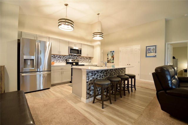 kitchen featuring decorative backsplash, a breakfast bar area, open floor plan, stainless steel appliances, and a sink