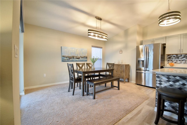 dining space with light carpet and baseboards