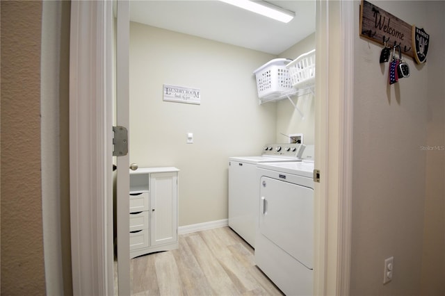 clothes washing area with washing machine and dryer, laundry area, baseboards, and light wood finished floors