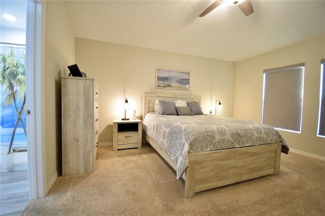 bedroom with ceiling fan, baseboards, and light colored carpet