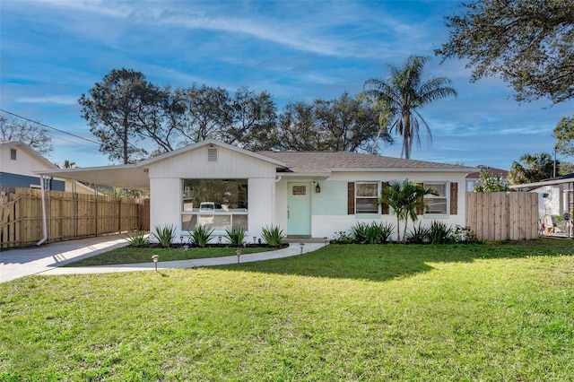 view of front facade with driveway, a carport, a front lawn, and fence