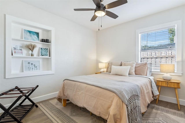 bedroom with ceiling fan, wood finished floors, and baseboards