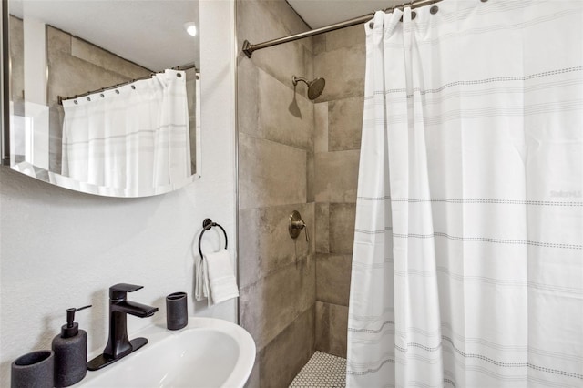full bathroom featuring a tile shower and a sink