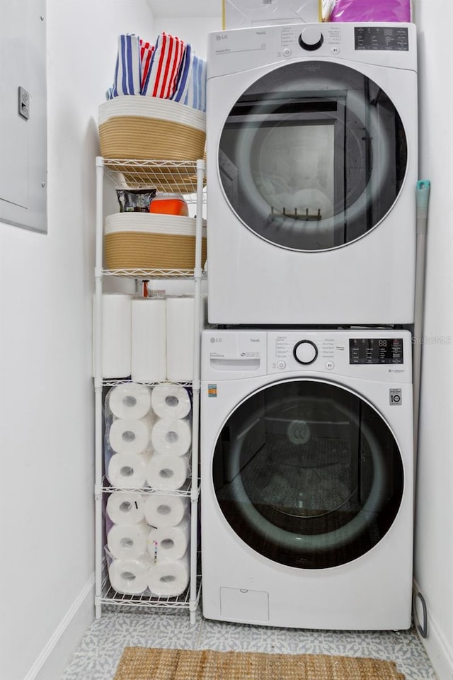 laundry area with baseboards, laundry area, stacked washer and clothes dryer, and electric panel