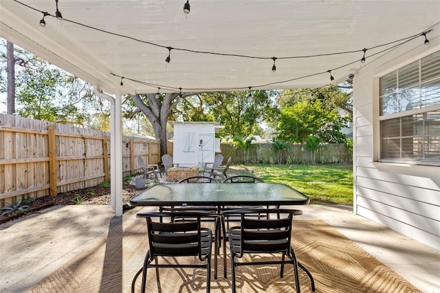 view of patio / terrace featuring a storage shed, a fenced backyard, outdoor dining area, and an outdoor structure
