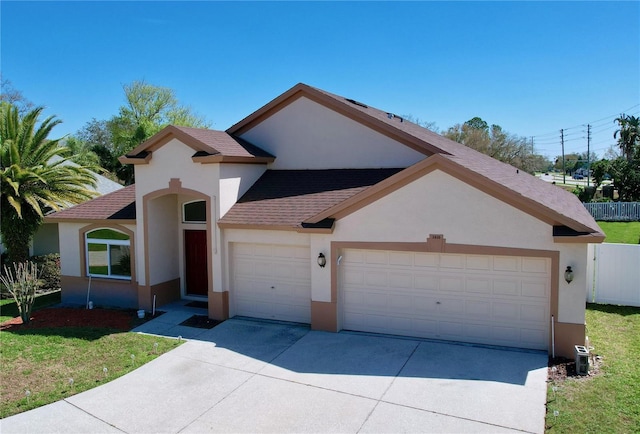 view of front facade with a garage, driveway, fence, and stucco siding