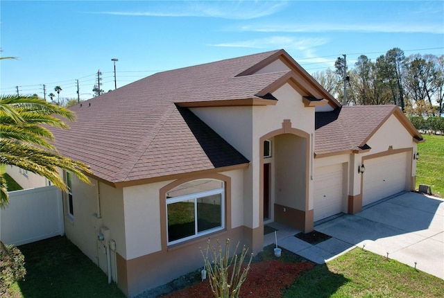 view of front of house featuring roof with shingles, stucco siding, concrete driveway, fence, and a garage