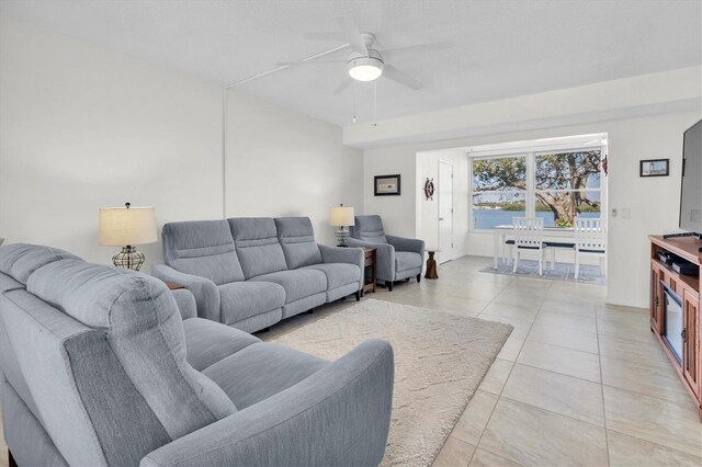 living area with light tile patterned floors and ceiling fan