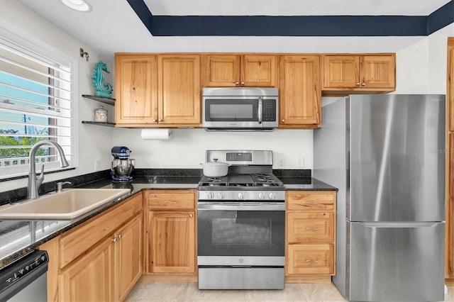 kitchen with stainless steel appliances, a sink, dark stone countertops, and open shelves