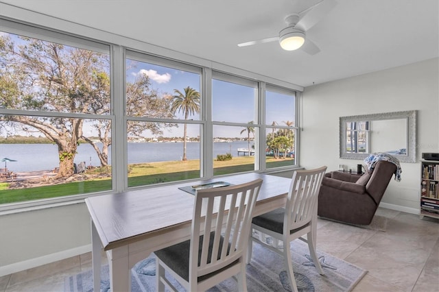 dining space with a water view, baseboards, and a ceiling fan