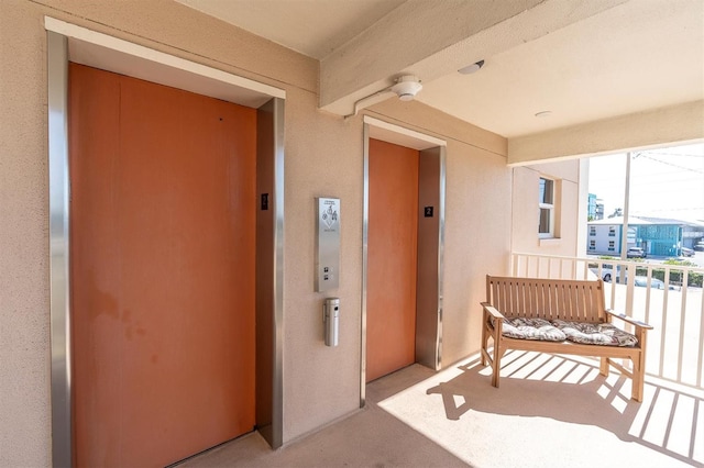 entrance to property featuring a balcony, elevator, and stucco siding