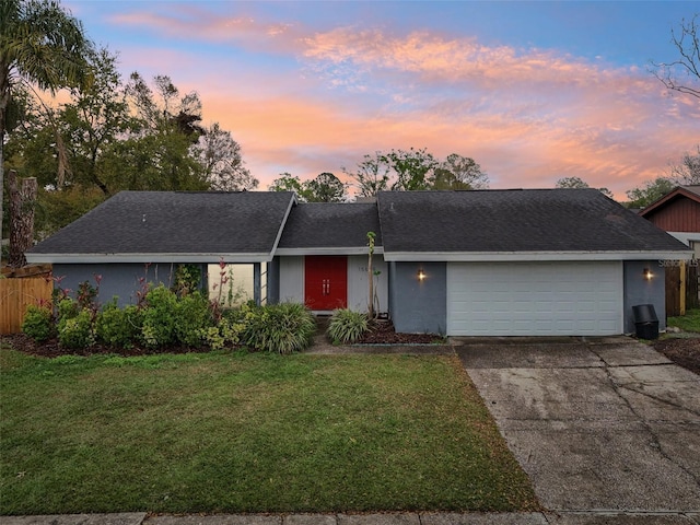 ranch-style house featuring fence, stucco siding, a front lawn, concrete driveway, and a garage