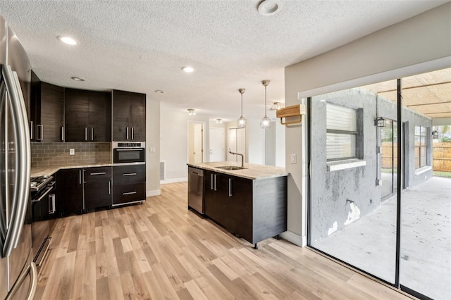 kitchen with a sink, tasteful backsplash, stainless steel appliances, light wood finished floors, and light countertops