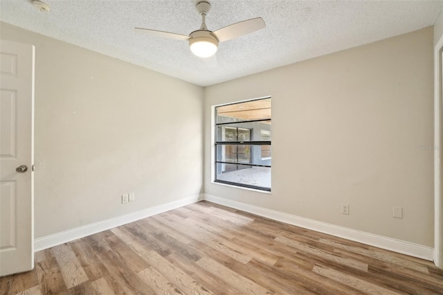 empty room featuring light wood-type flooring, baseboards, a textured ceiling, and ceiling fan