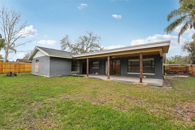 rear view of house featuring a yard, a fenced backyard, stucco siding, and a patio area