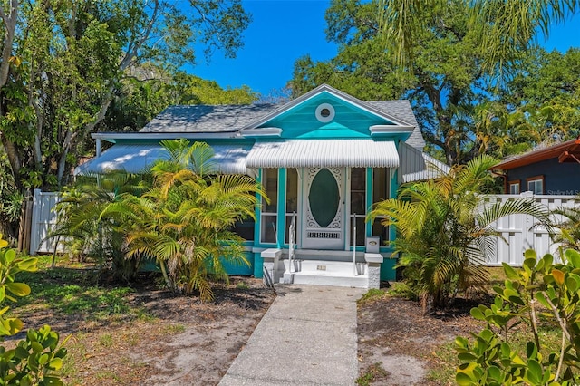 view of front of property featuring covered porch, fence, and roof with shingles