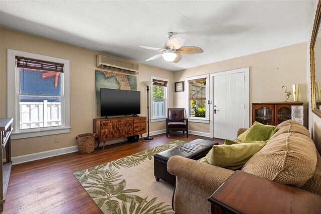 living area with ceiling fan, an AC wall unit, wood finished floors, and baseboards