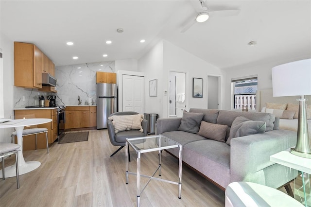 living area with lofted ceiling, ceiling fan, light wood-style flooring, and recessed lighting