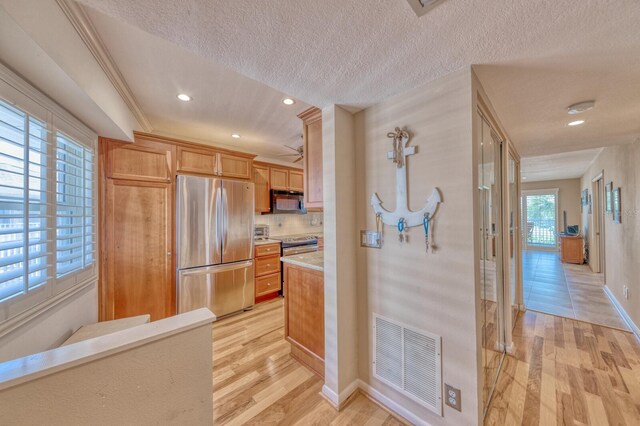 kitchen featuring a textured ceiling, stainless steel appliances, visible vents, light countertops, and light wood finished floors