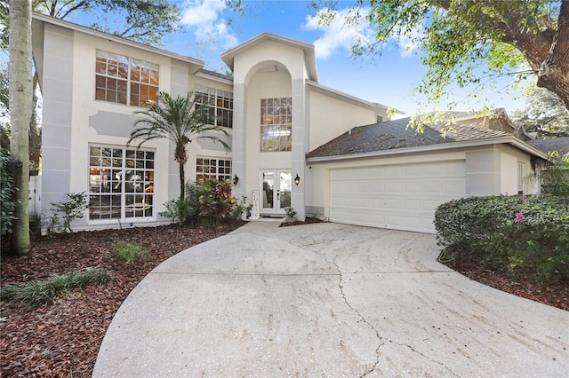 view of front facade featuring a garage, stucco siding, concrete driveway, and french doors