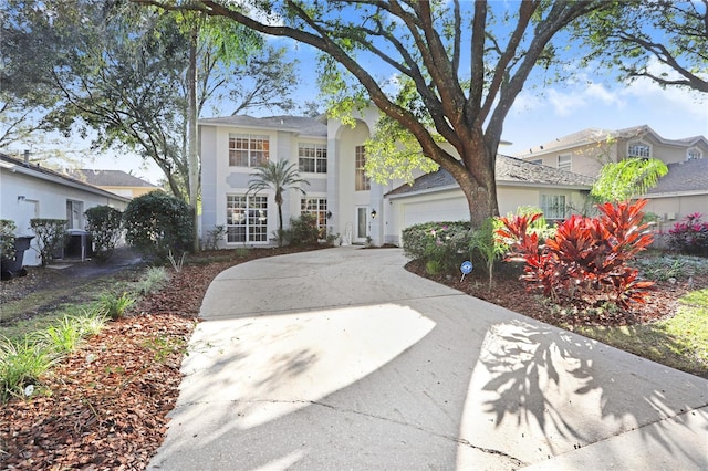 view of front of property featuring a garage, concrete driveway, cooling unit, and stucco siding