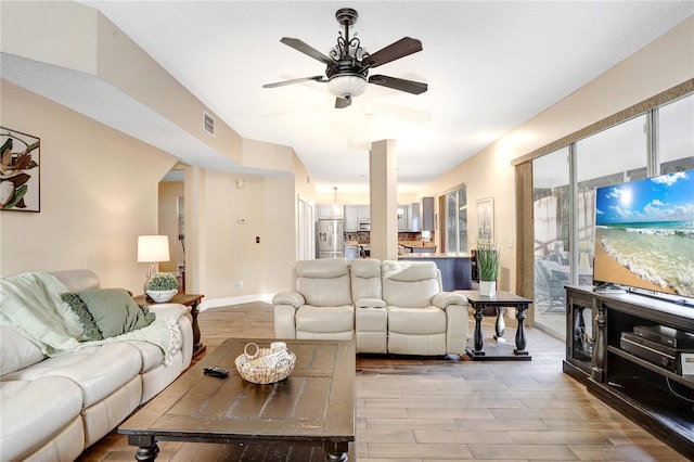 living room featuring ceiling fan, light wood finished floors, visible vents, and baseboards