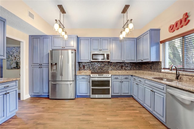 kitchen featuring visible vents, appliances with stainless steel finishes, light stone counters, light wood-type flooring, and a sink