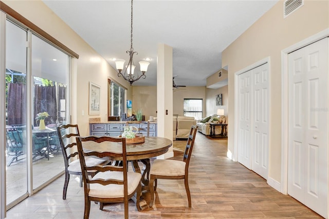 dining room with visible vents, light wood-style flooring, baseboards, and ceiling fan with notable chandelier