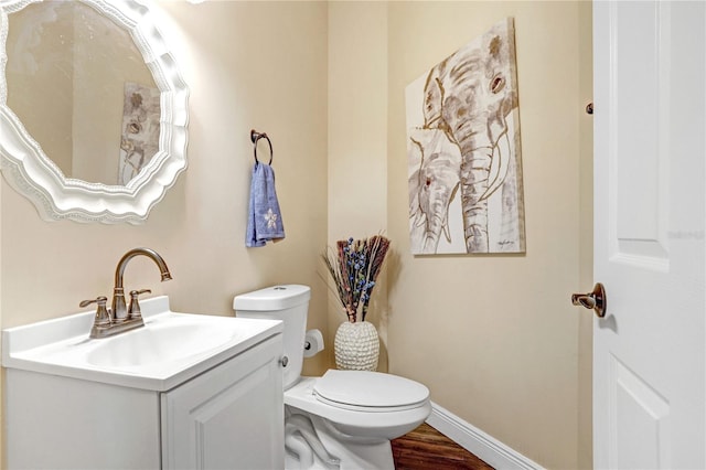 half bath with baseboards, vanity, toilet, and wood finished floors